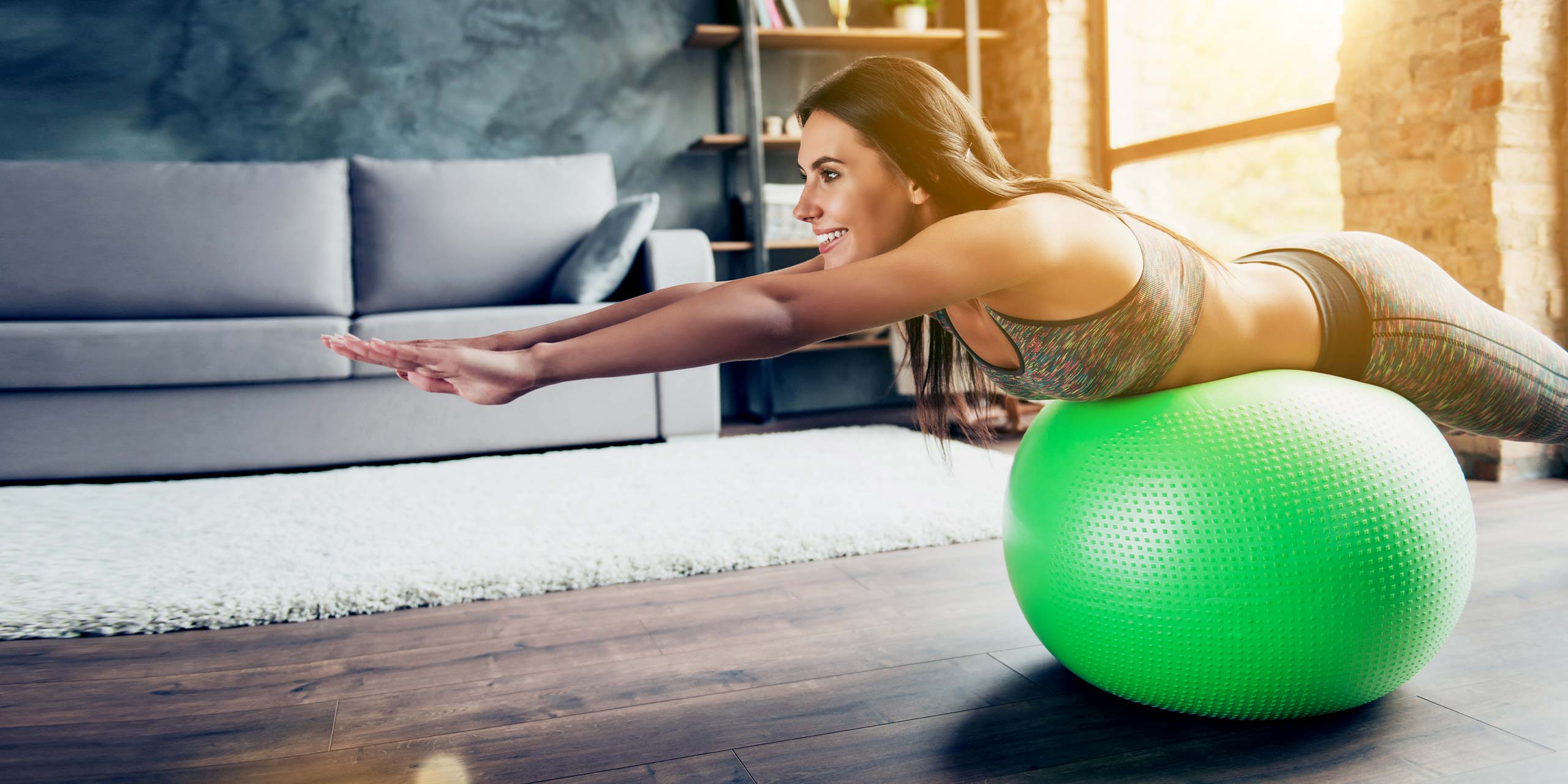 Frau balanciert Ihren Körper mit ausgestreckten Armen auf Gymnastikball